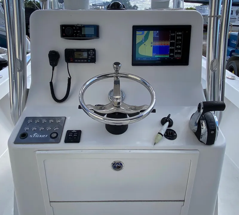 Slide: The Image of Control panel of a 2017 Stuart 25 West Coast boat with steering wheel and navigation equipment. - 13