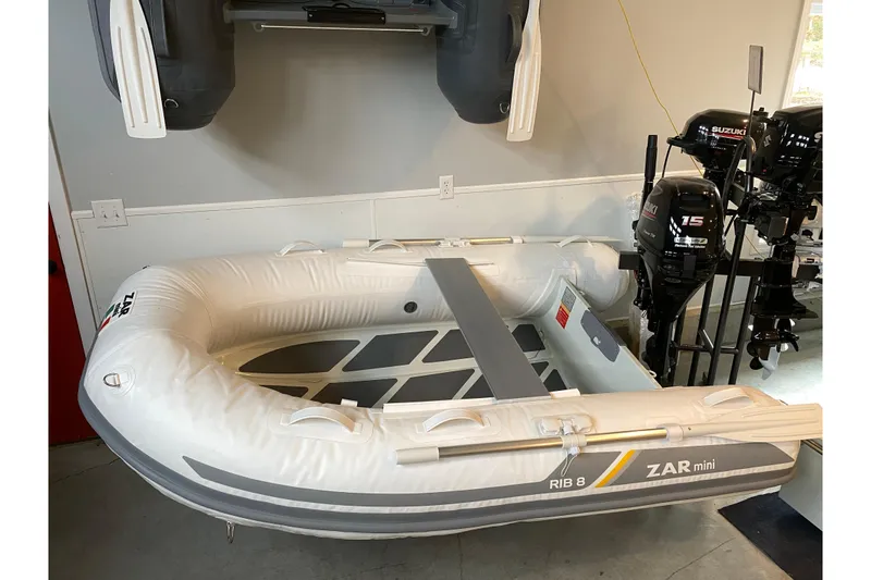 Slide: The Image of 2022 ZAR Mini RIB 8 HDL inflatable boat displayed indoors with Suzuki outboard motors. - 7