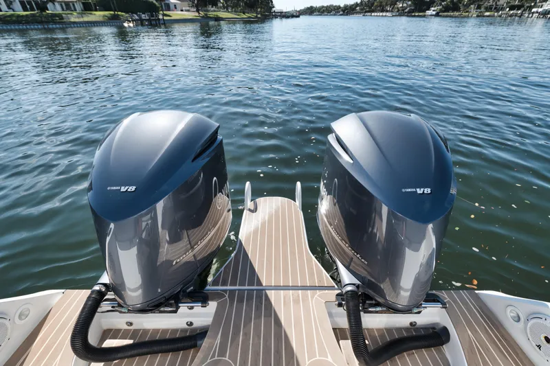 Slide: The Image of Twin outboard engines on a 2016 Powerplay Powerboats 42, docked on a serene lake. - 26