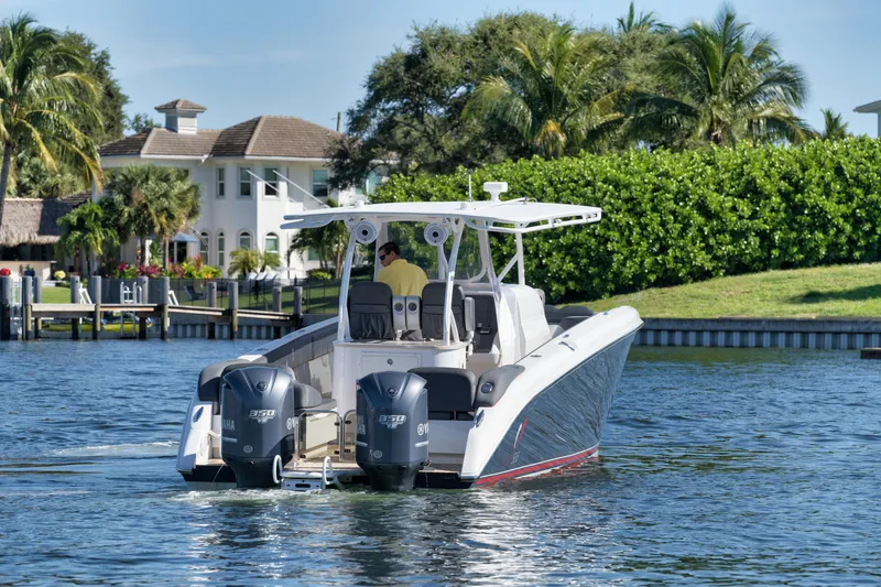 Slide: The Image of 2016 Powerplay Powerboats 42 cruising on a scenic waterway with lush greenery and waterfront homes. - 5
