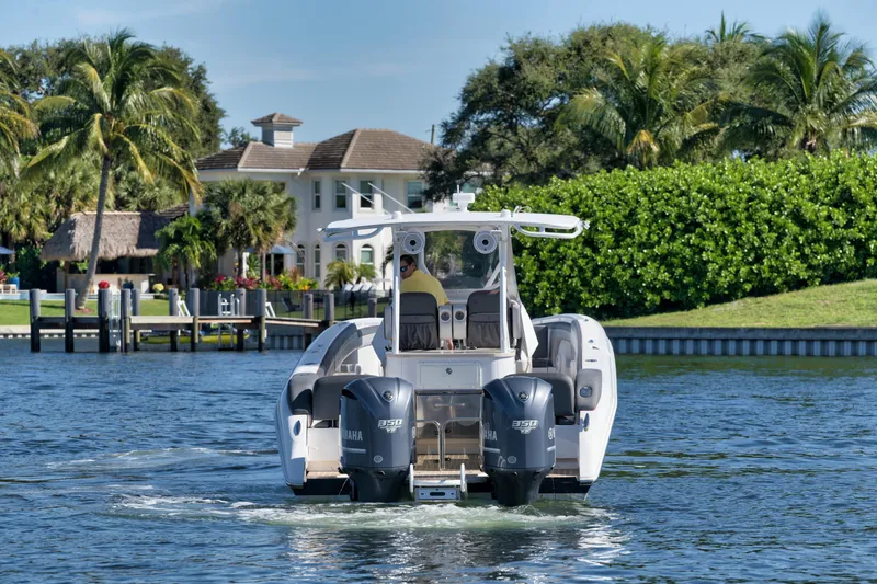 Slide: The Image of 2016 Powerplay Powerboats 42 cruising on a scenic waterway with lush greenery and waterfront homes. - 6