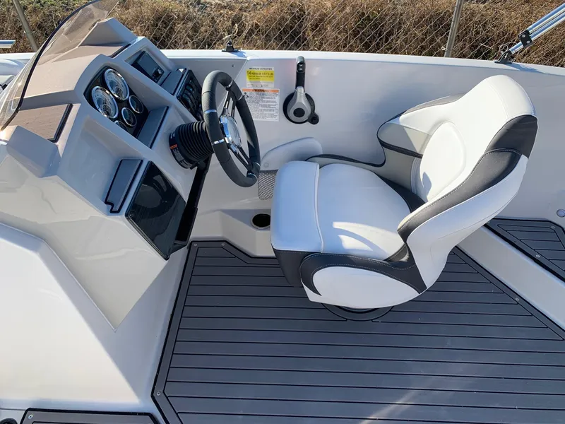 Slide: The Image of 2024 Starcraft SVX 211 boat cockpit with steering wheel and captain's chair. - 14