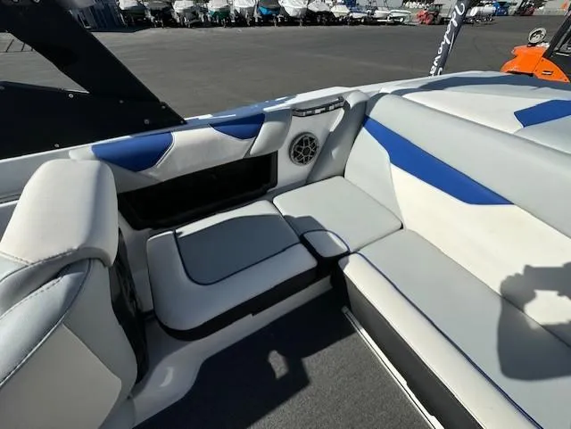 Slide: The Image of 2020 Axis A20 boat interior with white and blue seating, speaker, and storage compartment. - 12