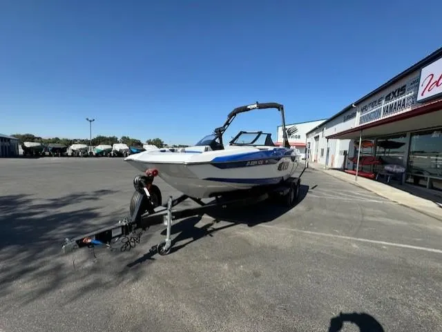 Slide: The Image of 2020 Axis A20 boat on trailer in dealership parking lot under clear blue sky. - 6