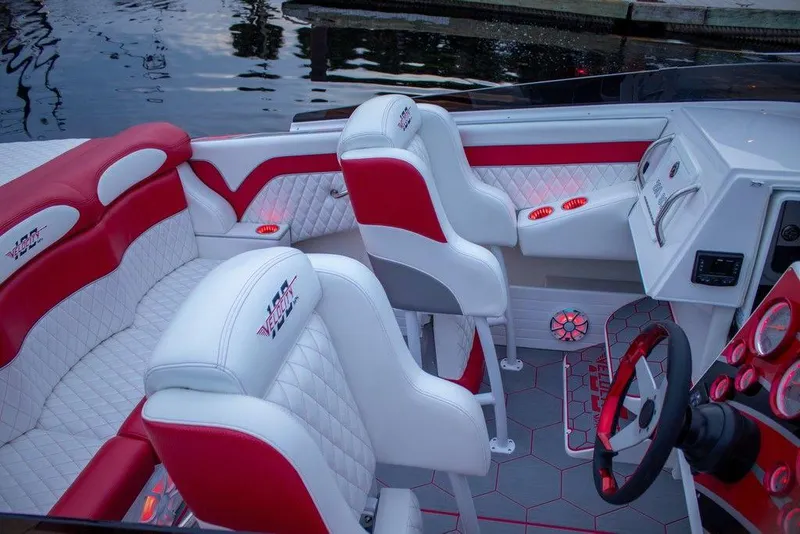 Slide: The Image of 2024 Velocity 322SC boat interior with red and white seating, modern dashboard, and water backdrop. - 6
