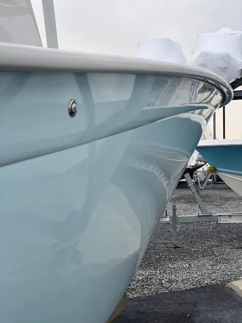 Slide: The Image of 2020 Cape Horn 24 XS boat, sleek blue hull, docked on gravel. - 13