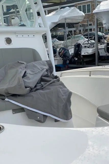 Slide: The Image of 2020 Cape Horn 24 XS boat interior with gray cover, docked near other boats. - 20