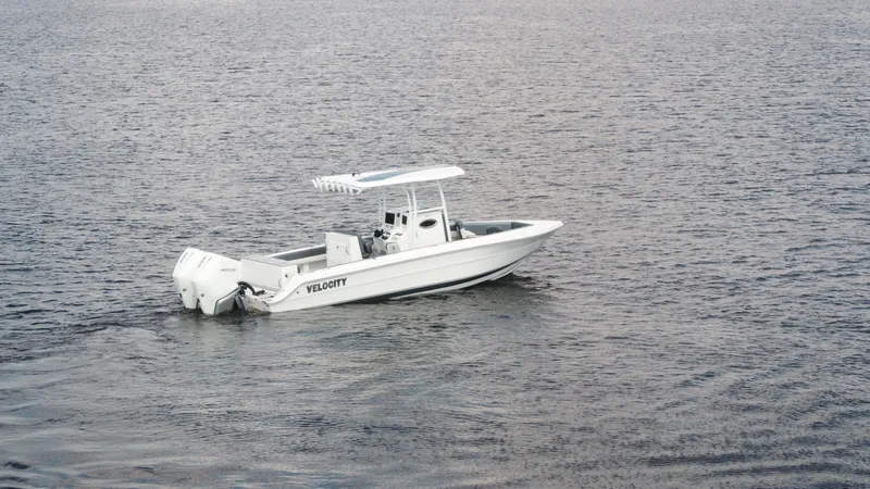 Slide: The Image of 2026 Velocity 262 CC boat on calm water, featuring twin outboard engines. - 25