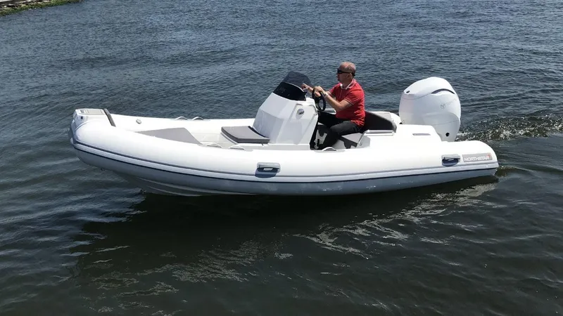 The Image of 2024 Northstar Axis 4.8 inflatable boat cruising on water. - 1