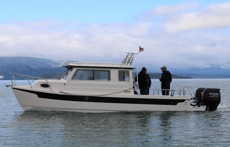 Slide: The Image of 2026 C-Dory TOMCAT 255 boat on water with two people onboard, scenic background. - 3