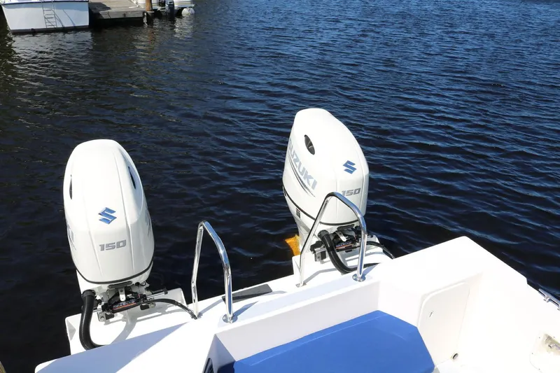 Slide: The Image of Twin Suzuki outboard engines on a 2026 C-Dory TOMCAT 255 boat, docked on calm water. - 7