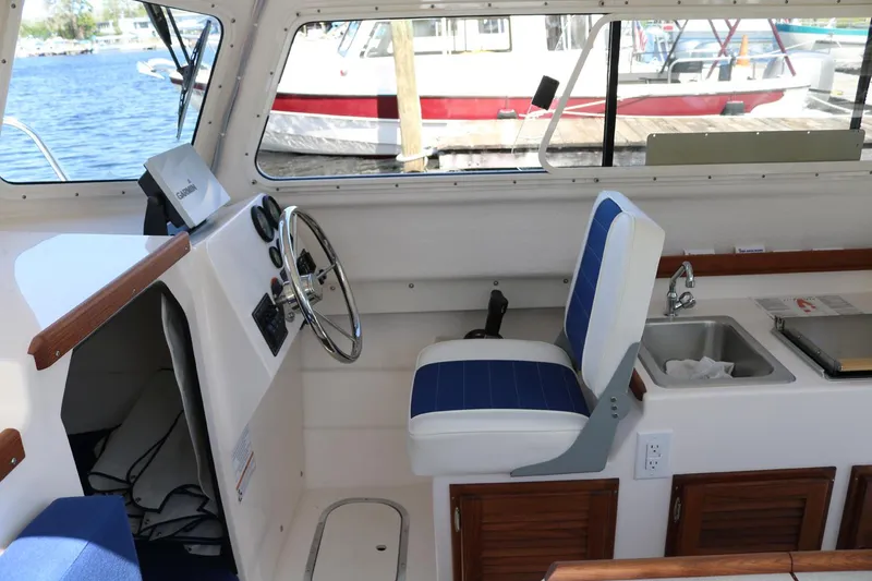 Slide: The Image of 2026 C-Dory TOMCAT 255 interior with helm, blue seat, and sink. - 9