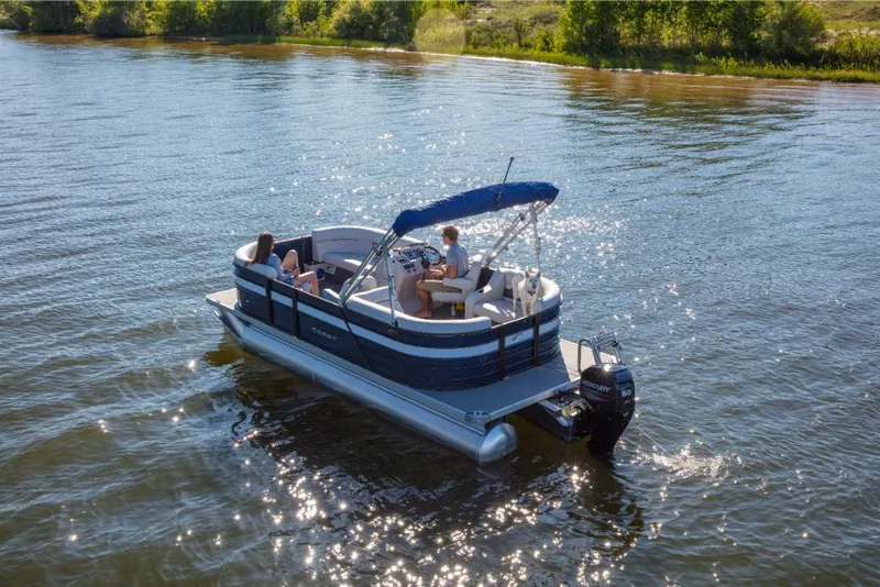 Slide: The Image of 2023 Crest Classic LX pontoon boat cruising on a sunny lake. - 1