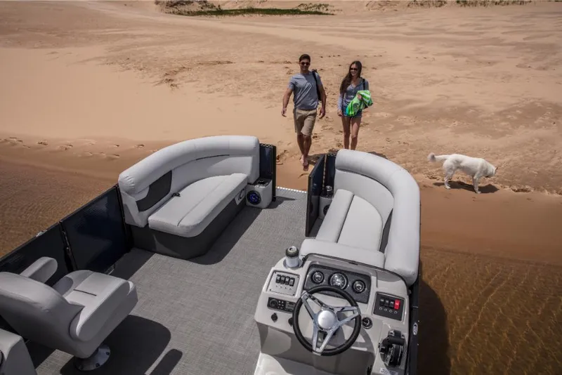 Slide: The Image of 2023 Crest Classic LX pontoon boat on sandy beach with couple and dog. - 11