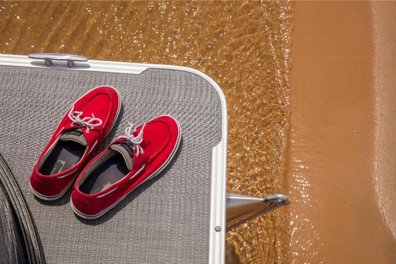 Slide: The Image of Red shoes on a 2023 Crest Classic LX boat deck by the water. - 12