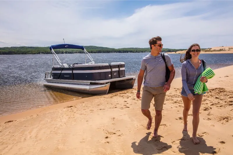 Slide: The Image of Couple walking on sandy beach near 2023 Crest Classic LX pontoon boat. - 14