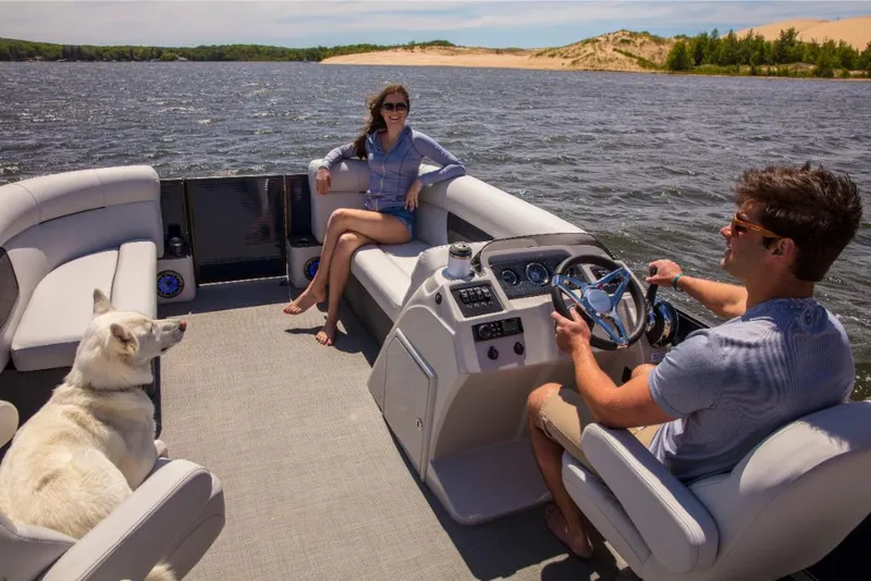 Slide: The Image of 2023 Crest Classic LX boat on a lake with two people and a dog. - 27
