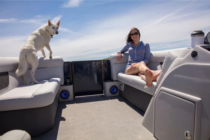 Slide: The Image of Woman and dog relaxing on a 2023 Crest Classic LX boat under a clear sky. - 28