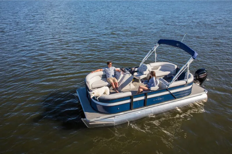 Slide: The Image of 2023 Crest Classic LX pontoon boat on a lake with passengers and a dog. - 3