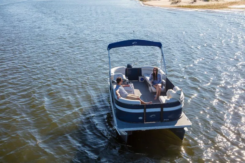 Slide: The Image of 2023 Crest Classic LX pontoon boat cruising on a sunny lake. - 6