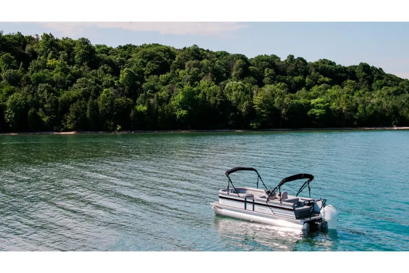 Slide: The Image of 2023 Crest Classic DLX pontoon boat on a serene lake with lush green forest background. - 4