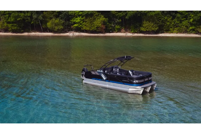 Slide: The Image of 2023 Crest Caribbean RS pontoon boat on clear lake water near forested shore. - 4