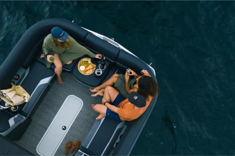 Slide: The Image of Three people relaxing on a 2023 Crest Caribbean RS boat with snacks. - 7