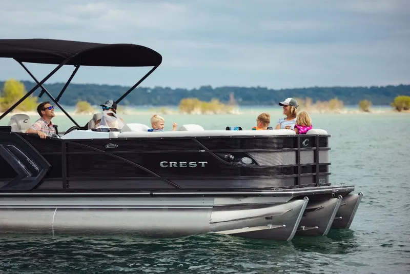Slide: The Image of 2023 Crest Caribbean Platinum pontoon boat with passengers on a lake. - 2