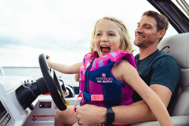 Slide: The Image of Father and daughter enjoying a ride on a 2023 Crest Savannah 270 boat. - 10
