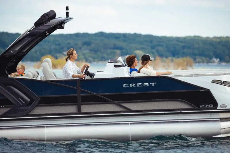 Slide: The Image of 2023 Crest Savannah 270 pontoon boat cruising on a lake with passengers. - 2