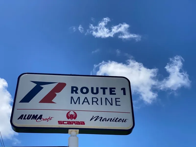 Slide: The Image of Route 1 Marine dealership sign with Alumacraft, Scarab, and Manitou logos under blue sky. - 13