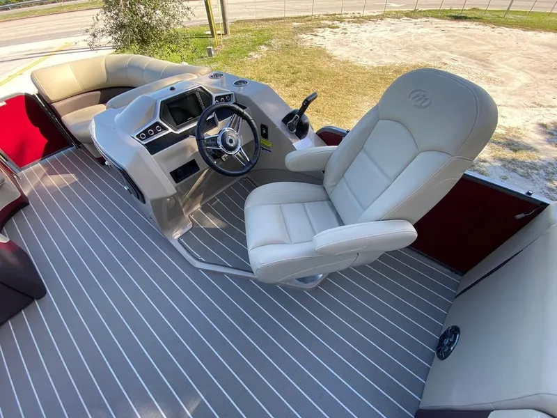 Slide: The Image of 2022 Manitou 23 Oasis SR VP boat interior with captain's chair and steering console. - 11