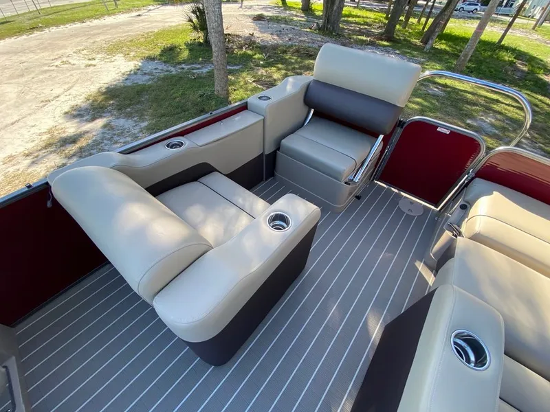 Slide: The Image of 2022 Manitou 23 Oasis SR VP boat interior with beige seating and cup holders. - 12