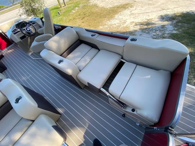 Slide: The Image of 2022 Manitou 23 Oasis SR VP pontoon boat interior with beige seating and striped flooring. - 16