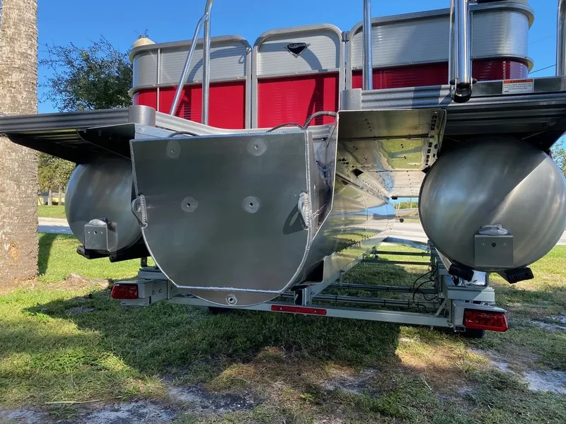 Slide: The Image of 2022 Manitou 23 Oasis SR VP pontoon boat rear view, showing aluminum pontoons and red paneling. - 26