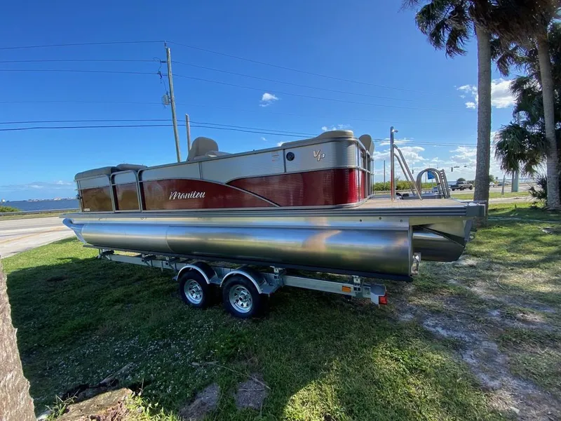 Slide: The Image of 2022 Manitou 23 Oasis SR VP pontoon boat on a trailer, parked near a waterfront. - 5