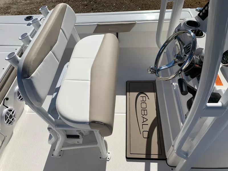 Slide: The Image of 2024 Robalo 226 Cayman boat interior with beige and white seating and steering console. - 4