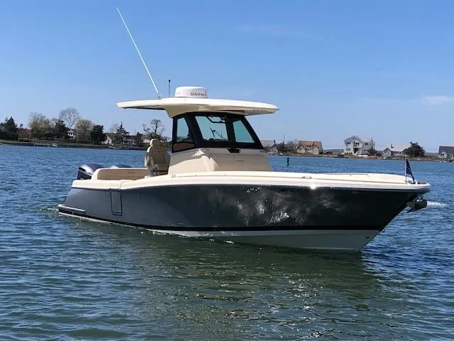 Slide: The Image of 2021 Chris-Craft Catalina 30 boat on calm water with houses in the background. - 4