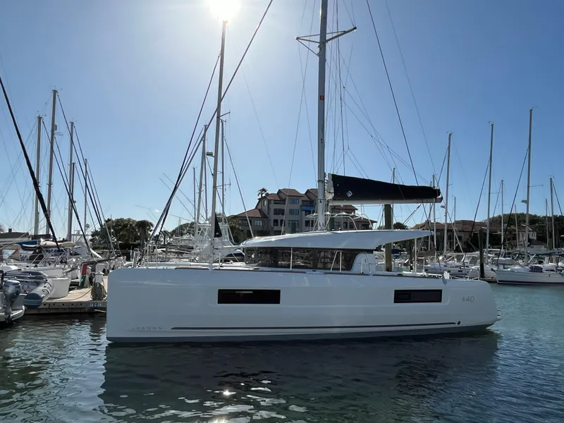 Slide: The Image of 2024 Lagoon 40 catamaran docked in a marina under clear blue skies. - 0
