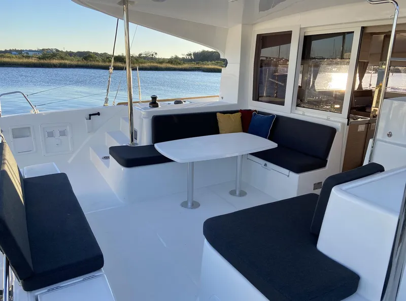 Slide: The Image of 2025 Lagoon 40 catamaran with spacious outdoor seating and table by the water. - 1