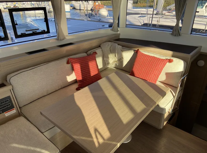Slide: The Image of Interior of 2025 Lagoon 40 catamaran with cozy seating and red cushions. - 4