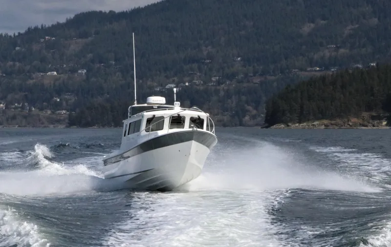 Slide: The Image of 2026 SeaSport Kodiak 2600 boat cruising on a scenic lake with forested hills. - 2