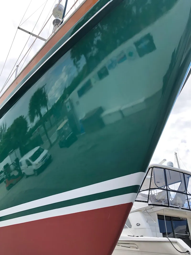 Slide: The Image of 1989 Little Harbor 54 sailboat with green hull and white stripe, docked near other boats. - 17