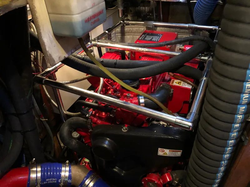 Slide: The Image of Engine room of a 1989 Little Harbor 54 yacht, featuring a red engine and various hoses. - 36