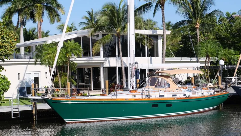 Slide: The Image of Little Harbor 54 sailboat, 1989 model, docked by a modern waterfront home with palm trees. - 46