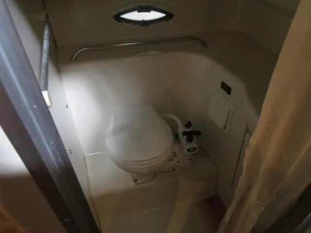 Slide: The Image of 2002 Bayliner 2655 Ciera Sunbridge boat bathroom with compact toilet and small window. - 15