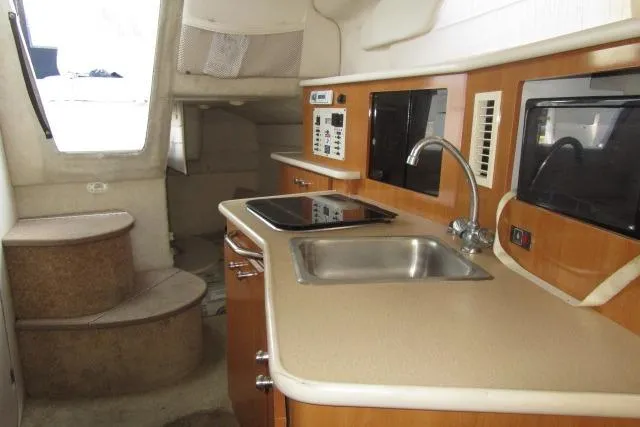 Slide: The Image of 2002 Bayliner 2655 Ciera Sunbridge interior with kitchenette, sink, and stairs. - 21