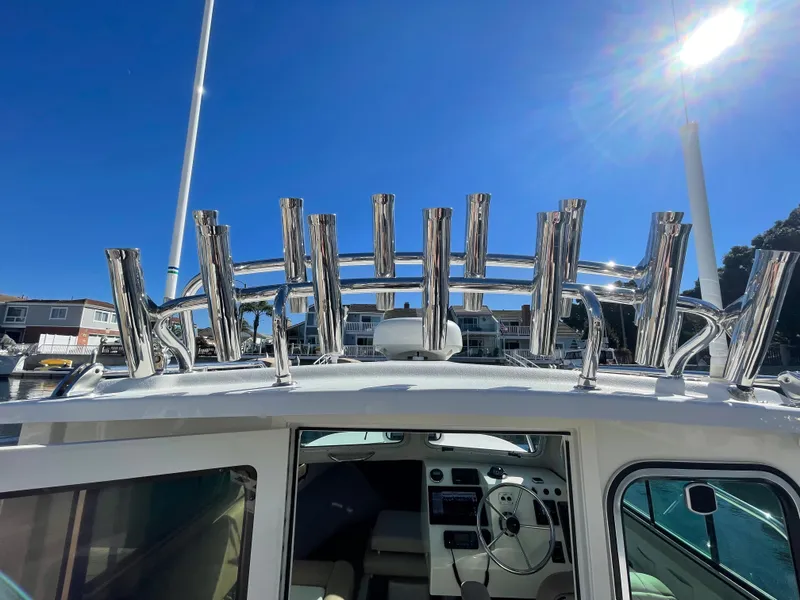Slide: The Image of 2017 Parker 2320 Sport Cabin boat with rod holders under clear blue sky. - 14