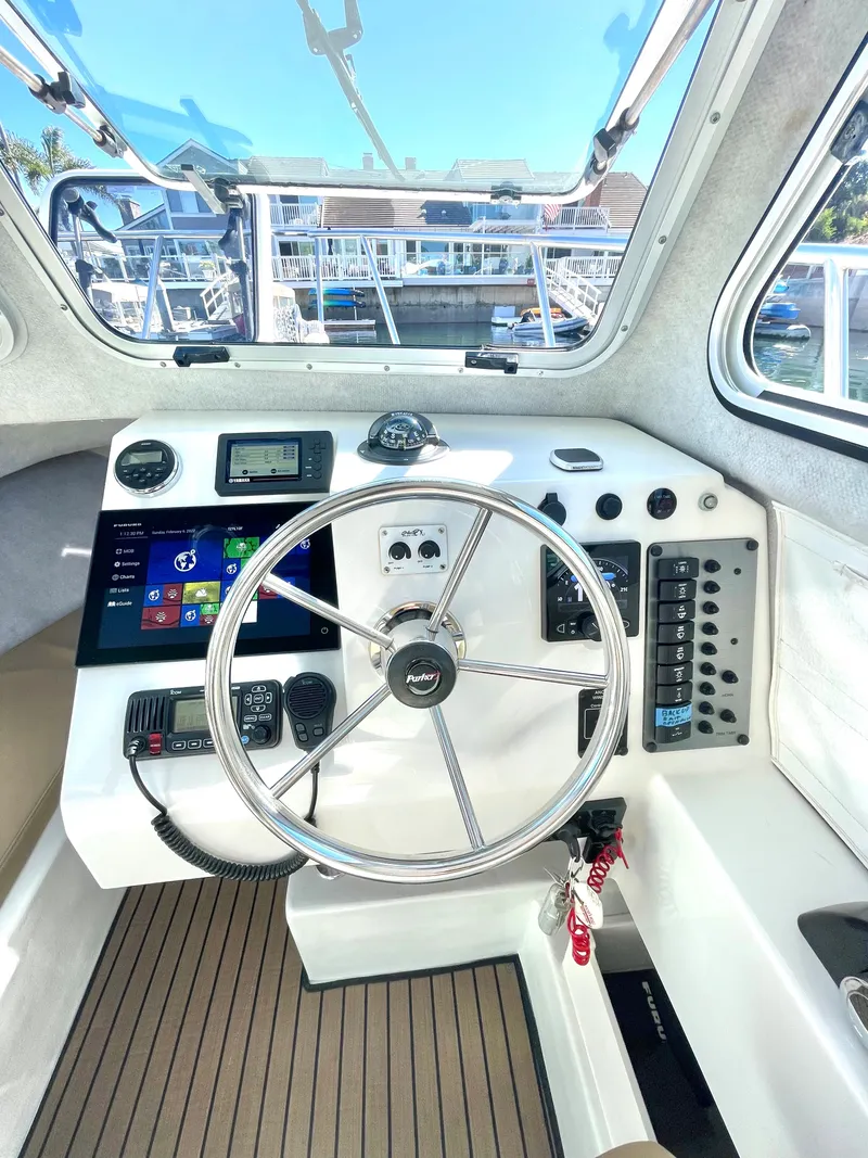 Slide: The Image of 2017 Parker 2320 Sport Cabin boat helm with steering wheel and control panel. - 2