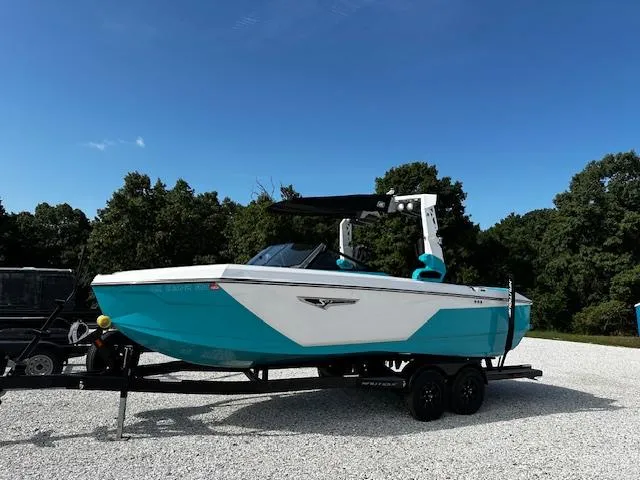 The Image of 2022 Nautique S23 boat in turquoise and white on a trailer, parked outdoors. - 0